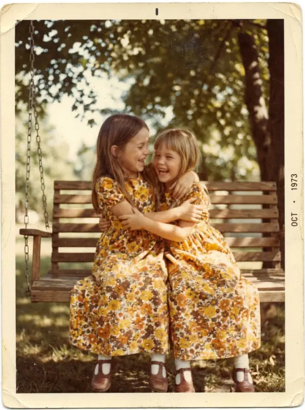 Two sisters giggling on a garden swing